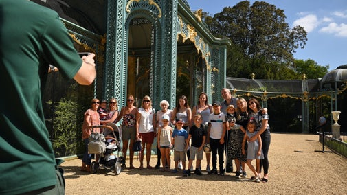 A man takes a photo of a group of visitors by the Aviary at Waddesdon Manor, Buckinghamshire